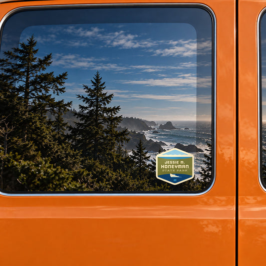 Jessie Honeyman sticker on the rear window of a van, reflecting a rocky coast with sea stacks