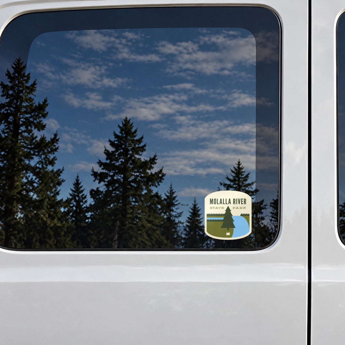 Molalla River sticker on the rear window of a van, reflecting conifers and blue sky