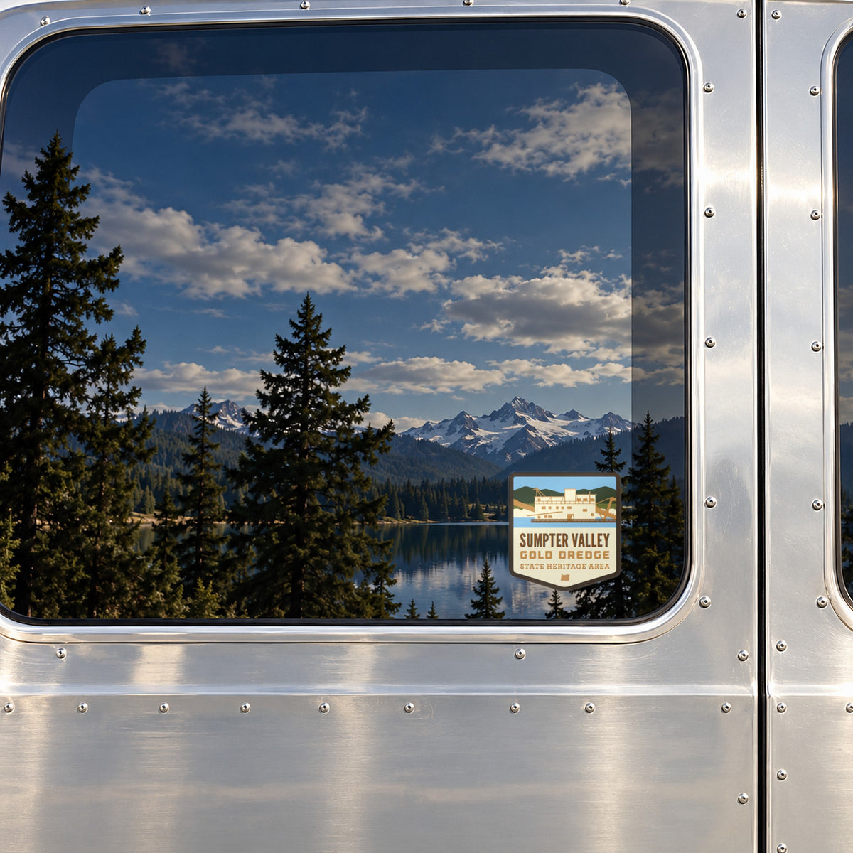 Sumpter Valley sticker on the rear window of a van, reflecting a lake under snowy peaks