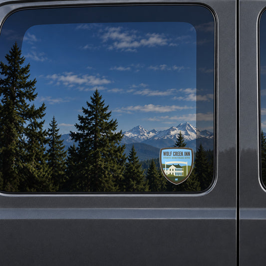 Wolf Creek Inn sticker on the rear window of a van, reflecting snowy Cascade peaks