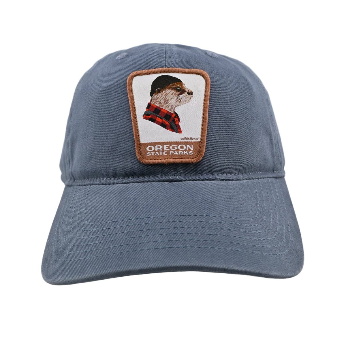 A dusty blue cotton baseball cap featuring a rectangular brown leather patch on the front with a riverotter wearing a red plaid shirt and the text 'OREGON WILDFANGS'.