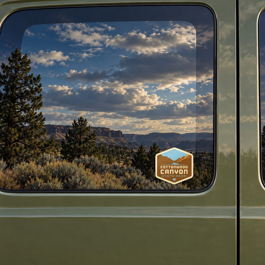 Cottonwood Canyon sticker on the rear window of a van, reflecting high-desert rimrock