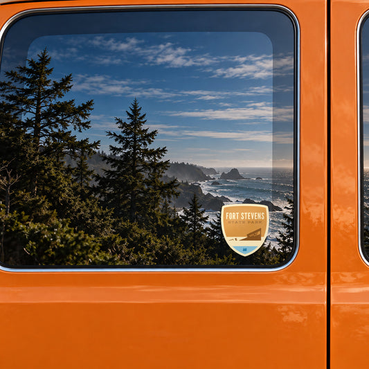 Fort Stevens sticker on the rear window of a van, reflecting a rocky coast with sea stacks