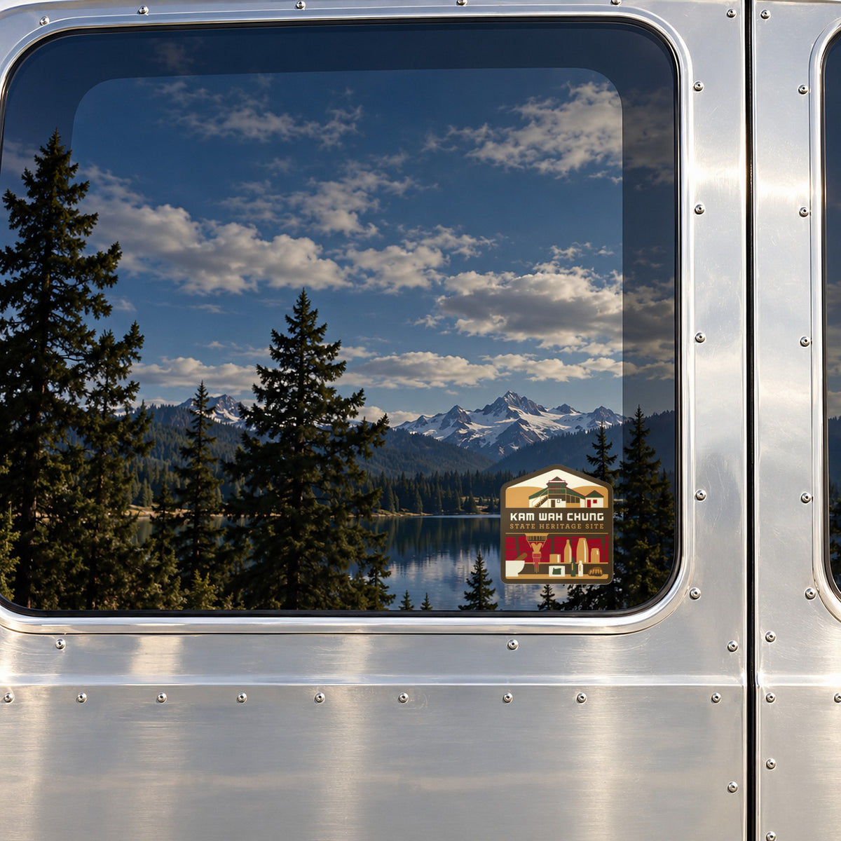 Kam Wah Chung sticker on the rear window of a van, reflecting a lake under snowy peaks