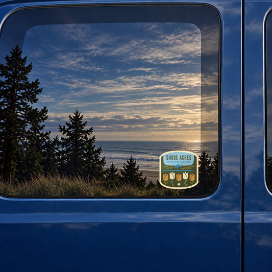 Shore Acres sticker on the rear window of a van, reflecting a beach at sunset