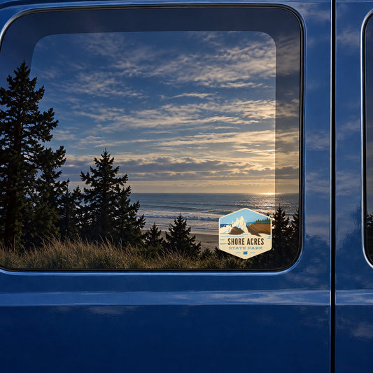 Shore Acres Waves sticker on the rear window of a van, reflecting a beach at sunset