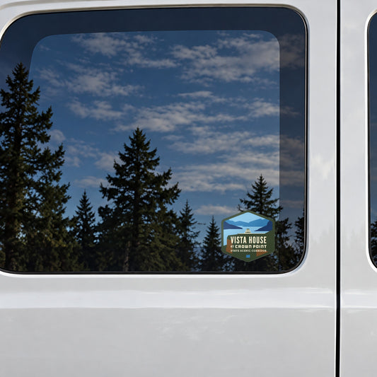 Vista House sticker on the rear window of a van, reflecting conifers and blue sky