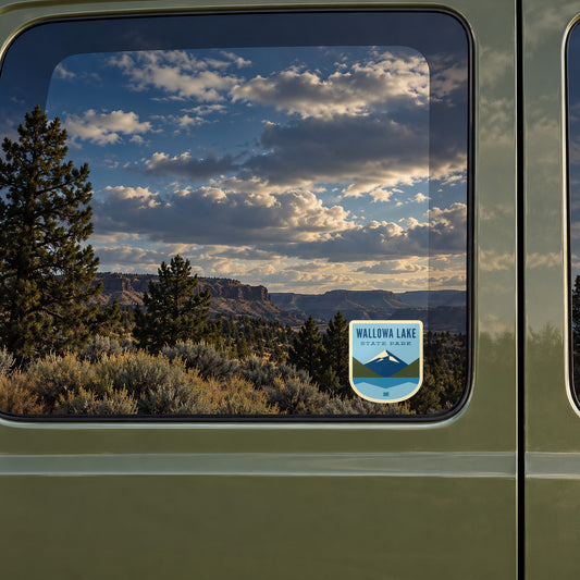 Wallowa Lake sticker on the rear window of a van, reflecting high-desert rimrock